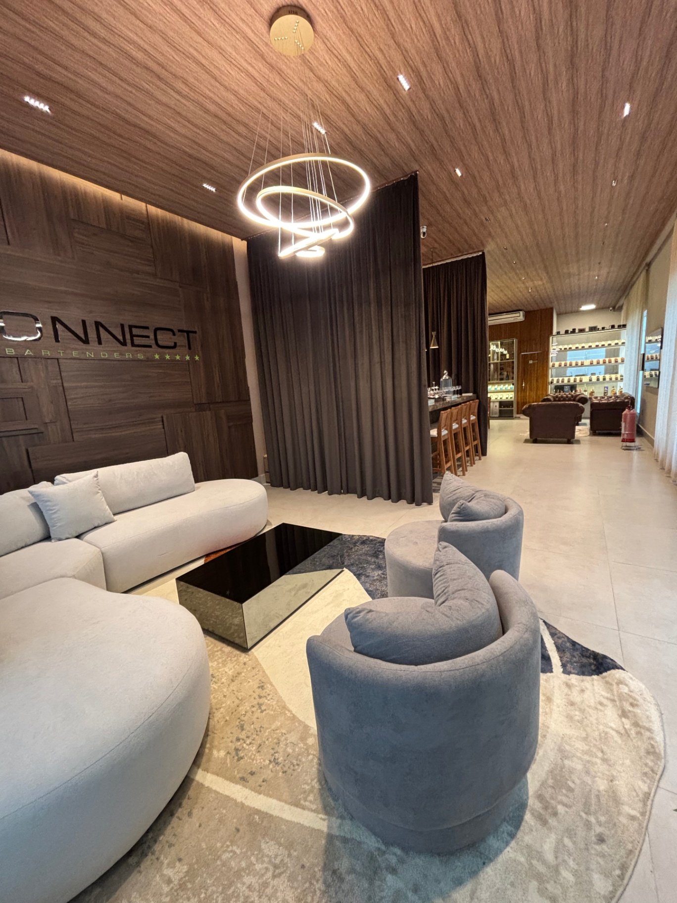 Sala de estar clara com sofás brancos e lustre de anéis luminosos